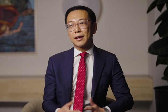 Anfeng He in a blue suit seated in the Allens office