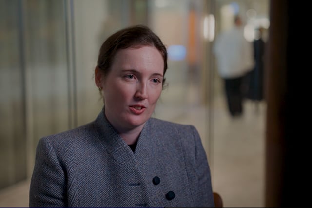 Elise Blume wearing a grey coat in the Allens office.